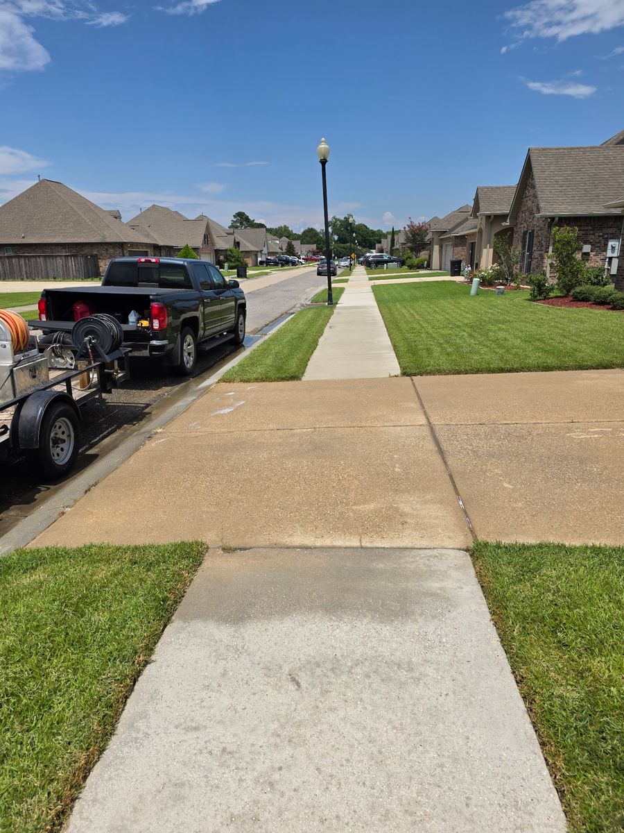 The same driveway and sidewalk after cleaning, concrete back to an even, bright finish